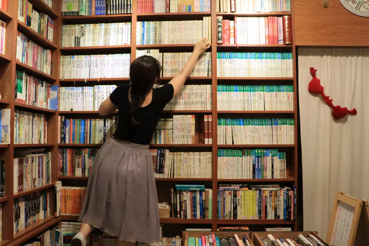 等閑書房二手書店藏書豐富，若瑜伸手從天花板高的書架拿書。圖片來源：山岳文化提供。